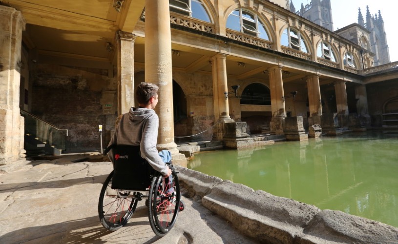Man in a wheelchair looking over the water at Roman Baths